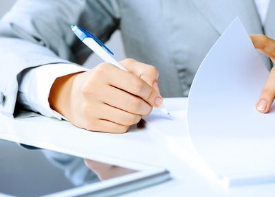 A person holding a pen and writing down two of the most common brand protection questions
