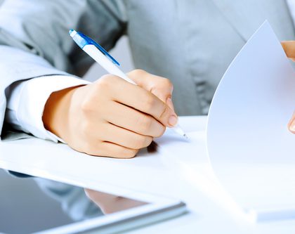 A person holding a pen and writing down two of the most common brand protection questions