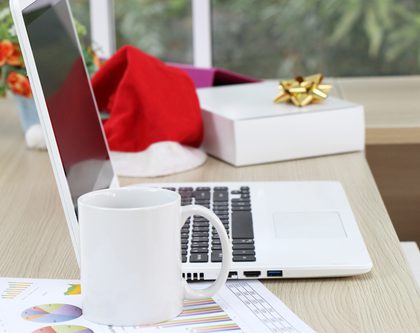 desk with laptop, box with a bow, mug, and a santa hat