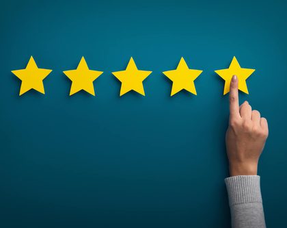 a row of yellow stars on a dark blue background and a hand pointing to one of them