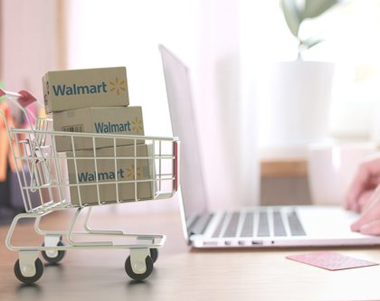 A small shopping cart with Walmart boxes and a person working on a laptop
