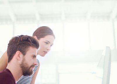 a man and a woman sitting in front of a computer in an office setting