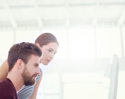 a man and a woman sitting in front of a computer in an office setting