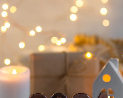 image with a wrapped gift, candles, string lights and a 2024 plaque
