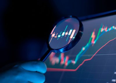 A tablet showing a graph with someone holding a magnifying glass