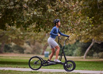 A woman riding StreetStrider through a scenic park