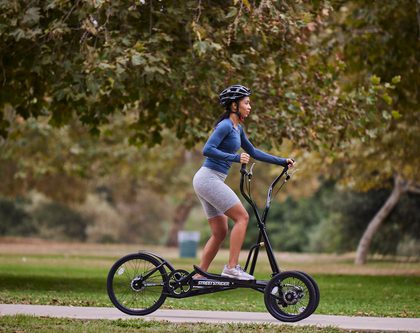 A woman riding StreetStrider through a scenic park