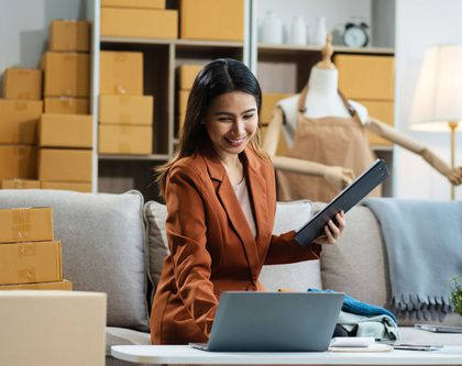 Woman sitting at a desk with clipboard and laptop