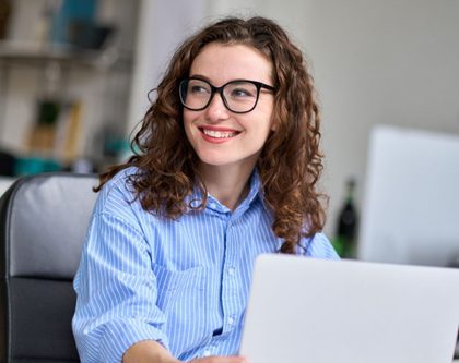 smiling woman sitting on a desk on a laptop