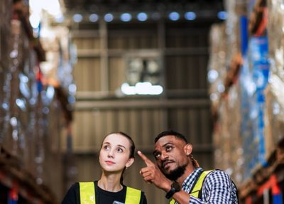 a man and a woman standing in a warehouse pointing