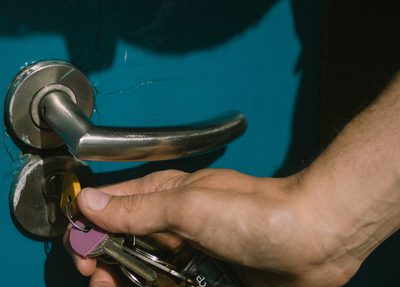 A hand unlocking a blue door with a set of keys