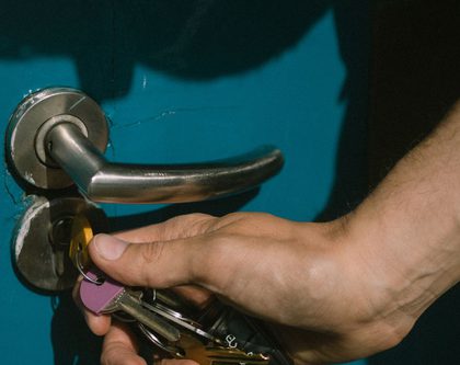 A hand unlocking a blue door with a set of keys
