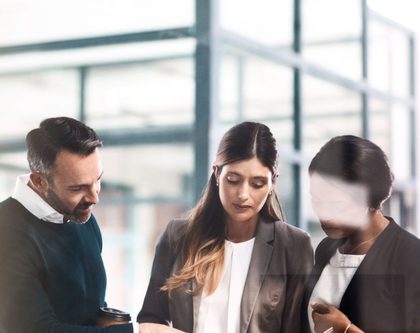 three people looking at a book in an office setting