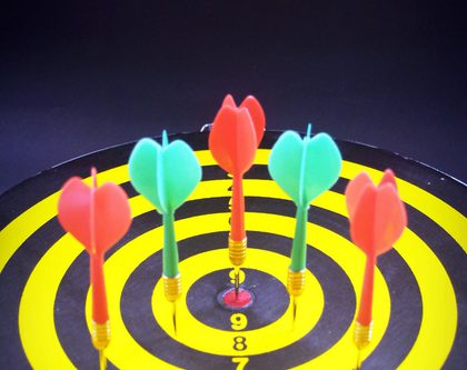 A dartboard featuring five darts perfectly positioned in the center