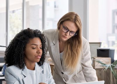 two women conversing and looking at a laptop