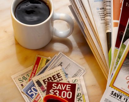stack of coupons + cup of coffee on a table