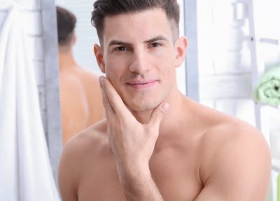 A clean shaved and handsome man standing in a bathroom