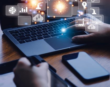 hands typing on a desk with a computer, smart phone and tablet