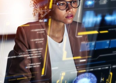 woman wearing glasses stares at a computer displaying a dashboard