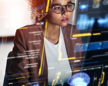 woman wearing glasses stares at a computer displaying a dashboard