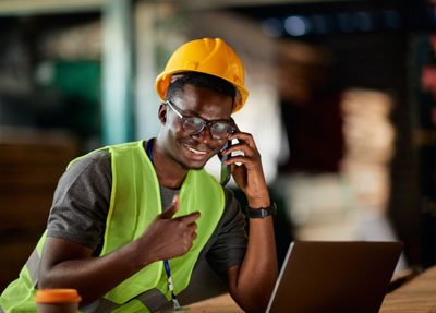 man in a hard hat and safety vest sits at product pallet