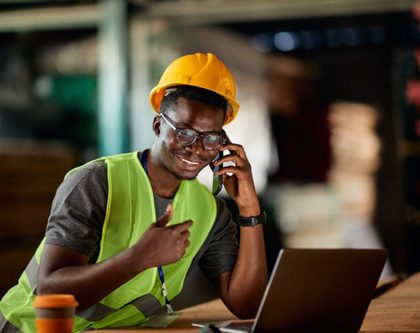 man in a hard hat and safety vest sits at product pallet