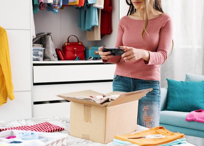 woman taking pictures of clothing items in a box to resell