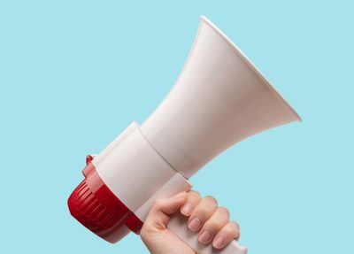 a person holds a megaphone against a blue background