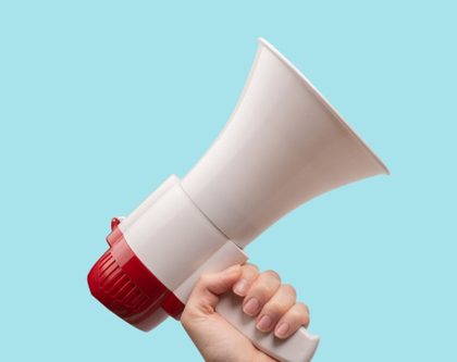 a person holds a megaphone against a blue background