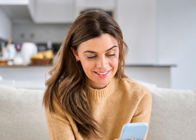 woman comfortably sitting on couch shopping on phone