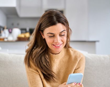 woman comfortably sitting on couch shopping on phone