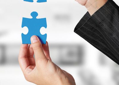 two hands holding blue puzzle pieces