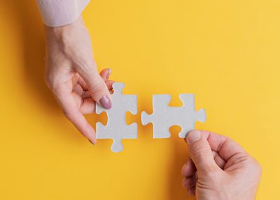 Two hands holding matching puzzle pieces