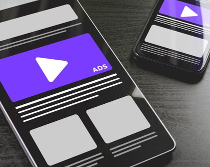 two mobile phones with video ads on a desktop
