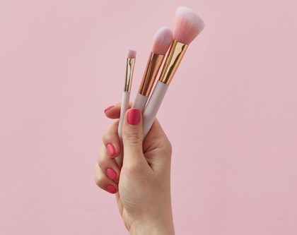 A female hand holding makeup brushes