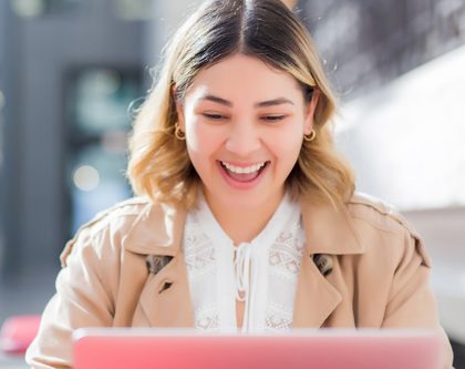 an image of a girl using a laptop computer outside and smiling