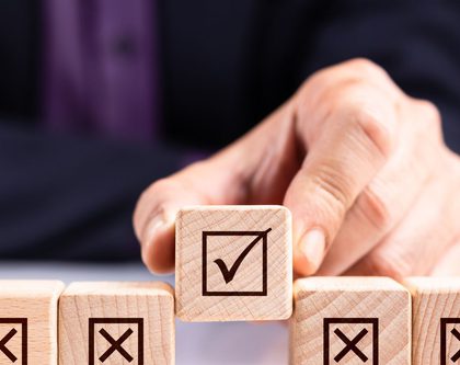 A person holding a wooden cube with checkmark sign