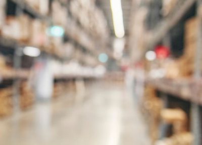 blurred view of a warehouse aisle filled with stacked boxes and shelves