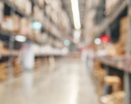 blurred view of a warehouse aisle filled with stacked boxes and shelves
