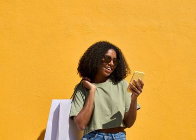 a woman holding a shopping bag while looking at her phone