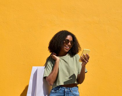 a woman holding a shopping bag while looking at her phone