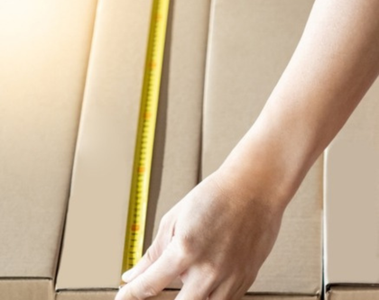 a person measuring cardboard boxes with a tape measure