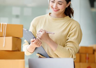 woman working at a desk with a laptop surrounded by cardboard boxes
