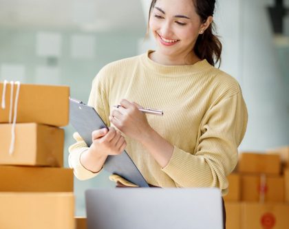 woman working at a desk with a laptop surrounded by cardboard boxes