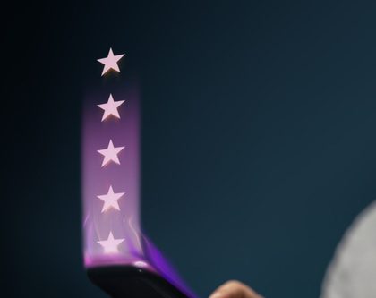 a person holds a smartphone with five glowing stars emerging from the screen