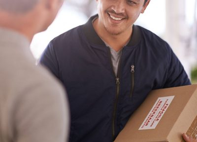 delivery man holds a box while another man signs for the delivery