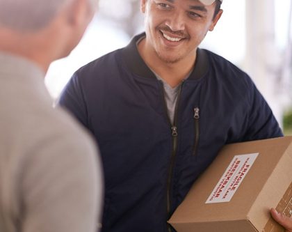 delivery man holds a box while another man signs for the delivery