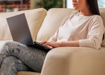 a woman sitting on a couch focused on her laptop