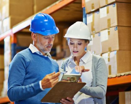 a man and woman in a warehouse reviewing a clipboard
