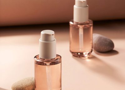 two beauty product bottles against a beige background